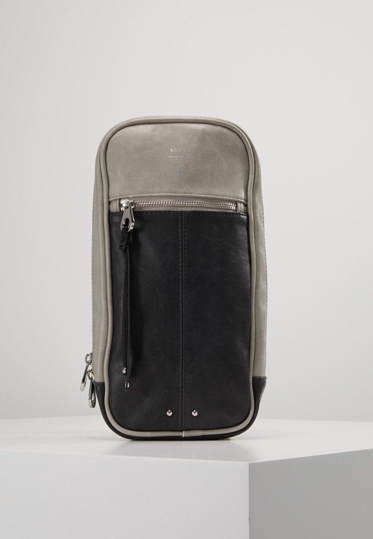 Skórzany plecak z szarym wierzchem i czarną dolną częścią, wyposażony w przednią kieszeń na zamek błyskawiczny, srebrne akcesoria i zaokrąglone krawędzie.