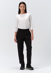 Zwarte elastische tailleband broeken met een relaxte pasvorm, gecombineerd met een aansluitend wit longsleeve shirt, gedragen met zwarte wandelschoenen.