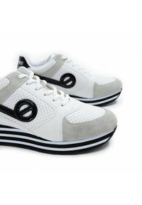 Sneakers met een witte leren bovenkant, grijze suède accenten, geperforeerde details, een zwart logo en een gestreepte zwart-witte zool.