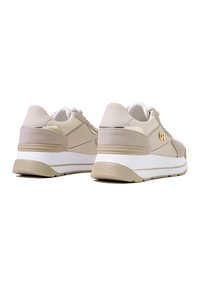 Sneaker beige con una combinazione di pelle liscia e suede, caratterizzate da una suola intermedia bianca e un accento del logo dorato sul tallone.