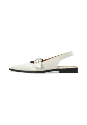 Zapato tipo slingback con un acabado crema brillante, punta afilada y una hebilla decorativa. Suela plana negra con una textura suave.