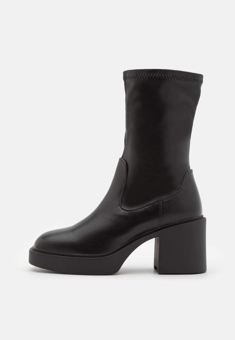 Botte en cuir noir mi-mollet avec bout arrondi, talon bloc épais et couture supérieure lisse, montrée en profil latéral sur fond blanc.