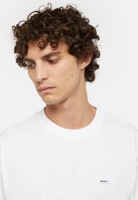 Hvid bomulds crewneck sweatshirt med et lille brandet mærke på venstre brystområde, glat tekstur og en klassisk pasform.