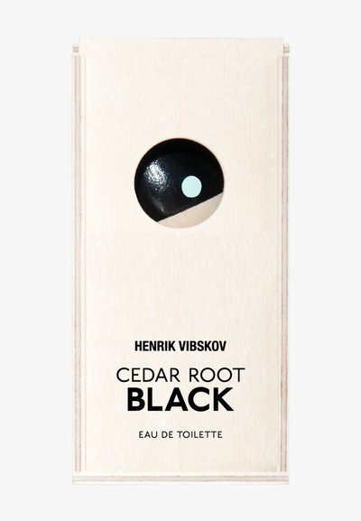 El envase de Cedar Root Black Eau de Toilette presenta un diseño de madera clara y suave con un punto negro brillante y un acento verde menta.
