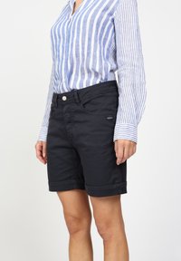 Tmavě námořnické šortky z bavlněné směsi, s klasickým střihem, ohrnutým lemem a předními kapsami. Kombinovány s modrobílým pruhovaným tričkem.