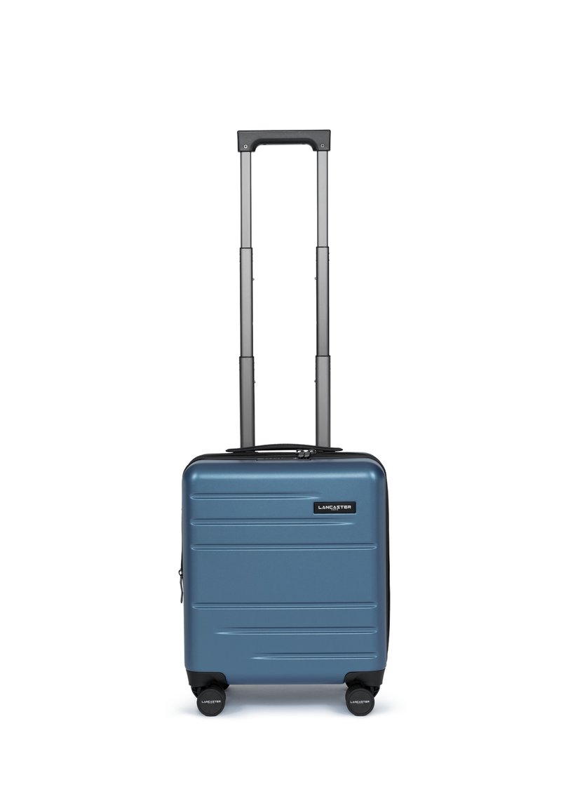 Valigia rigida blu con forma rettangolare elegante, manico nero telescopico e quattro ruote nere; presenta un motivo a scanalature orizzontali.