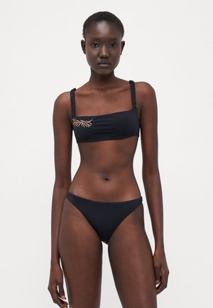 Mustat bikinit, joissa on bandeau-toppi rypytetyillä olkaimilla ja hienovaraisella kultaisella brodeerauksella, täydentävät yhteensopivat matalavyötäröiset alaosat.
