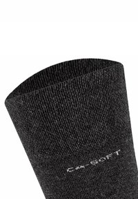 Calcetín negro hasta el tobillo con un acabado de punto texturizado, mostrando un borde superior redondeado y una marca blanca a lo largo del costado. Material ligero.