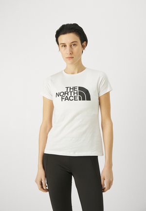 Biała koszulka z krótkim rękawem z wyraźnym czarnym logo "The North Face" w zaokrąglonym wzorze na piersi.