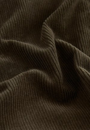 Brun ribbad tyg med en mjuk, texturerad yta, som visar ett vågigt mönster skapats av upphöjda vertikala linjer.