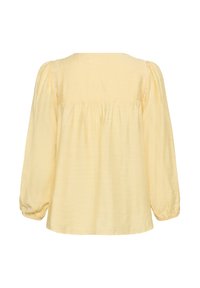 Blouse jaune pâle à manches longues avec détail froncé au dos, poignets élastiqués et bordure délicate en dentelle le long des coutures d'épaule.