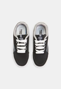 Sneaker nere con lacci bianchi, accenti grigi e un logo blu. Fodera in tessuto testurizzato, colletto imbottito e suole in gomma bianche.