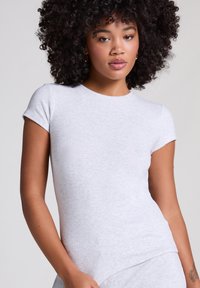 Vaaleanharmaa slim fit -t-paita, joka on valmistettu pehmeästä, tekstuurista kankaasta. Paidassa on lyhyet hihat ja pyöreä kaulus, jossa on hienovaraisia ribattuja yksityiskohtia.