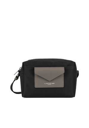 Trousse de toilette rectangulaire noire avec rabat de poche en cuir gris à l'avant et fermeture éclair argentée, marque Lancaster Paris.