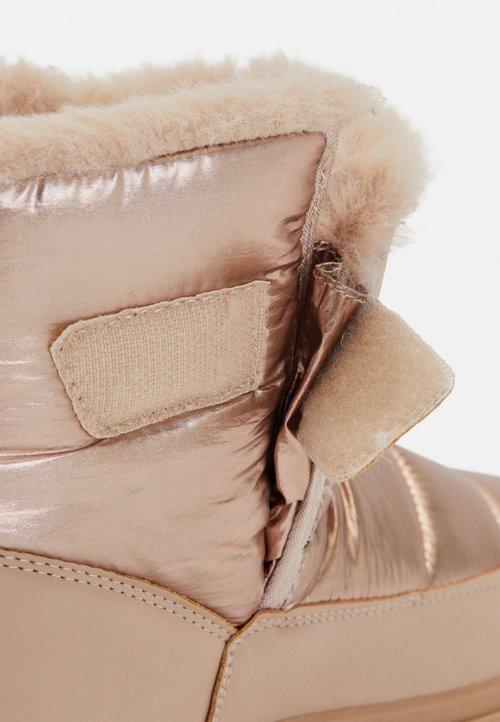 Stivale in tessuto trapuntato rosa chiaro, foderato in pelliccia, con cinturino in Velcro e suola liscia; finitura lucida con dettagli di cucitura minimi.