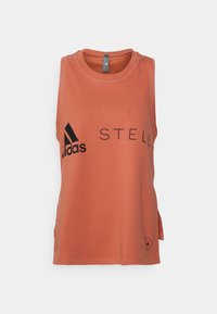 Persikofärgad ärmlös träningslinne i bomullsmaterial, rund hals, med svart "adidas STELL"-logotyp och små sidoklyftor.