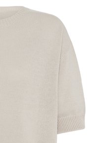 Gros plan d’un pull en tricot beige clair montrant la manche courte et le détail du col rond côtelé.