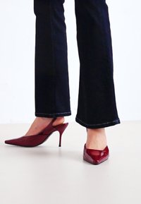 Burgundské lodičky na vysokom podpätku s špicatou špičkou a otvorenou zádou, s lesklým povrchom a úzkym stiletto podpätkom.
