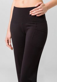 Black high-waisted leggings with a smooth texture, featuring a side pocket and stretchable fabric for comfort and ease of movement.