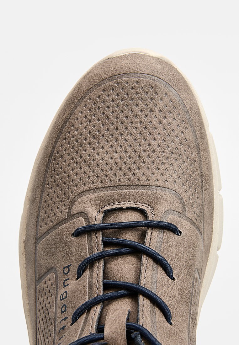 Zapatilla de ante marrón claro con área de punta perforada, cordones negros y suela beige, vista desde arriba.