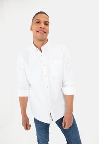 Witte, knoopsluiting overhemd met lange mouwen en een borstzak, voorzien van lichtbruine knopen en een casual pasvorm. Draag je met blauwe spijkerbroeken.