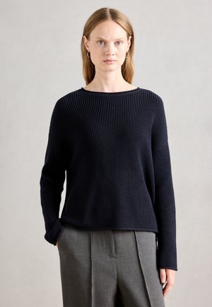 Navy ribbed knit sweater with a wide neckline and long sleeves, paired with gray tailored trousers. Smooth texture, casual fit.