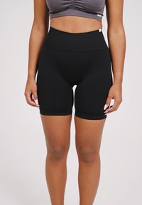 Černé vysoké cyklistické kraťasy vyrobené z elastického materiálu, s přiléhavým střihem a hladkou texturou, s délkou ke kolenům.