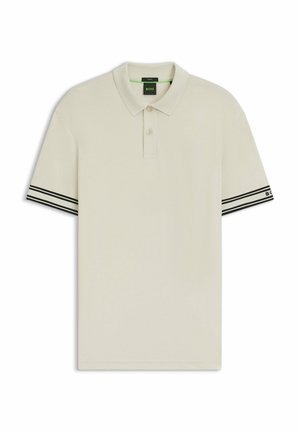 Ljust beige pikétröja gjord av mjukt material. Har korta ärmar med svart och vit randig accent vid ärmsluten. Tvåknappslång.