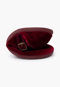 Housse de chapeau en velours bourgogne avec un détail de boucle en bronze. Forme douce et arrondie, dotée d'un extérieur texturé et d'un intérieur moelleux pour la protection.