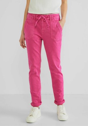 Pantalons ajustés fuchsia avec une taille à cordon, deux poches avant et des poignets roulés, associés à des baskets blanches.