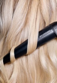 Czarna stożkowa lokówka o eleganckim designie, owinięta jasnoblond włosami, prezentująca gładką teksturę i miękkie loki.