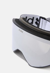 Bliz skidglasögon med en böjd, spegel-lins, svart ram och mjuk skumvaddering. Utrustad med ett vitt elastiskt band med svart logotyptext.