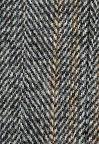 Wool herringbone fabric featuring a mix of black, white, and orange-brown threads, displaying a textured, zigzag pattern.