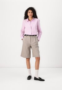 Long-sleeve pink and white striped shirt, beige tailored shorts, black belt, black loafers, and white scalloped socks. Simple outfit design.