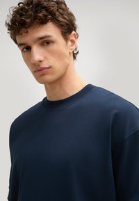 Marineblauwe katoenen t-shirt met een ronde hals, korte mouwen en een ontspannen pasvorm, met een zachte textuur en subtiele stikseldetails.