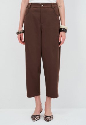 Pantalons larges marron en tissu lisse avec poches avant, taille haute et fermeture à bouton. Associés à des chaussures à talons pointus au motif léopard.