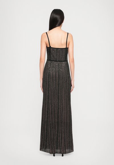 Black maxi dress with thin straps, vertical metallic stripes, fitted bodice, and flared hem, featuring a textured surface and subtle sheen.