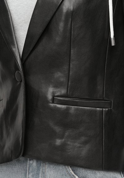Μαύρο δερμάτινο σακάκι με λεία υφή, κλασικούς γιακάδες τύπου notch, κλείσιμο με ένα μεγάλο κουμπί και δύο μπροστινές τσέπες.