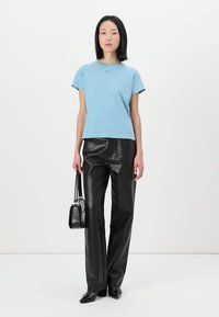 Ανοιχτό μπλε κοντομάνικο μπλουζάκι σε συνδυασμό με μαύρα παντελόνια από συνθετικό δέρμα και μαύρη τσάντα. Απαλή υφή, χαλαρή εφαρμογή και απλός σχεδιασμός.