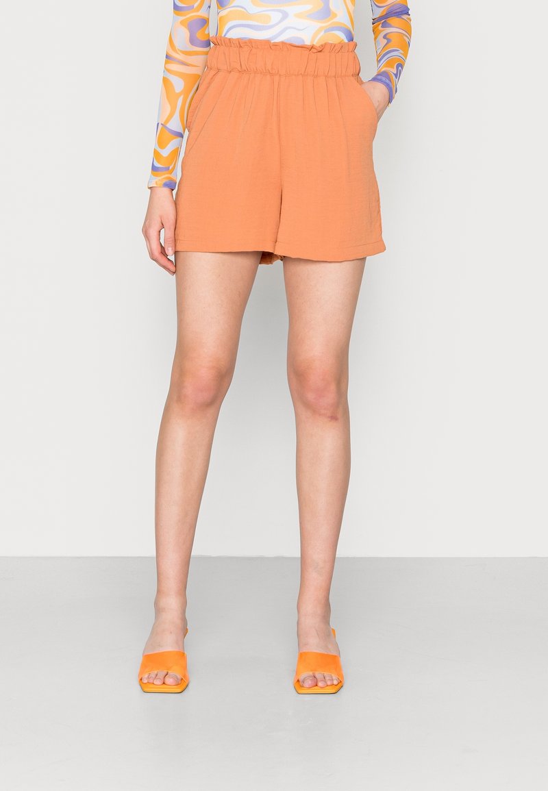 Oranje shorts met hoge taille, een elastische tailleband, zijzakken en een gestructureerde stof. Gecombineerd met feloranje sandalen met een vierkante neus.