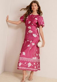 Roze bloemen maxi-jurk met pofmouwen en een strakke taille. Heeft witte bloemenpatronen en ingewikkelde randen aan de zoom.