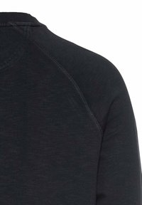 Zwarte longsleeve shirt met een gestructureerde stof, een ribgebreide halslijn en raglanmouwen met contrasterende stiksels.