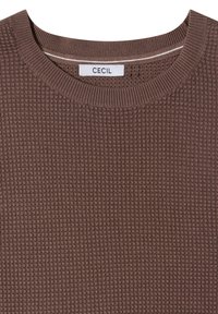 Pull marron en maille gaufrée avec col rond côtelé et une étiquette de marque blanche indiquant "CECIL" à l'intérieur du col.