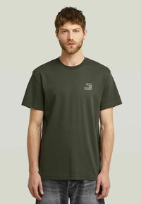 Olijfgroene t-shirt van katoen, met een ronde hals en korte mouwen. Bevat een klein logotag op de linkerborst. Klassieke pasvorm.