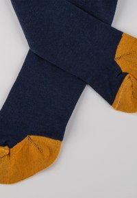Marineblaue Socken mit strukturierter Oberfläche, die kontrastierende Akzente in senfgelb an Spitze und Ferse aufweisen und ein Farbkombinationsdesign schaffen.