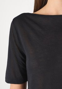 Black, short-sleeve t-shirt made of soft, lightweight fabric, featuring a wide neckline and smooth texture with a subtle sheen.