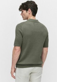 Kortärmad polo t-shirt i olivgrön, med ribbad textur, platt krage och en figurnära passform. Sömmen är något kortad med ett fast band.