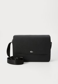 Sac en cuir noir à bandoulière avec une texture lisse, un rabat avant, un accent logo argenté et une bandoulière en tissu réglable.