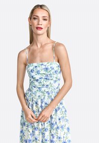 Bloemendress met blauwe en groene patronen, getailleerde bodice en A-lijn rok, voorzien van dunne bandjes en een textuurstof.