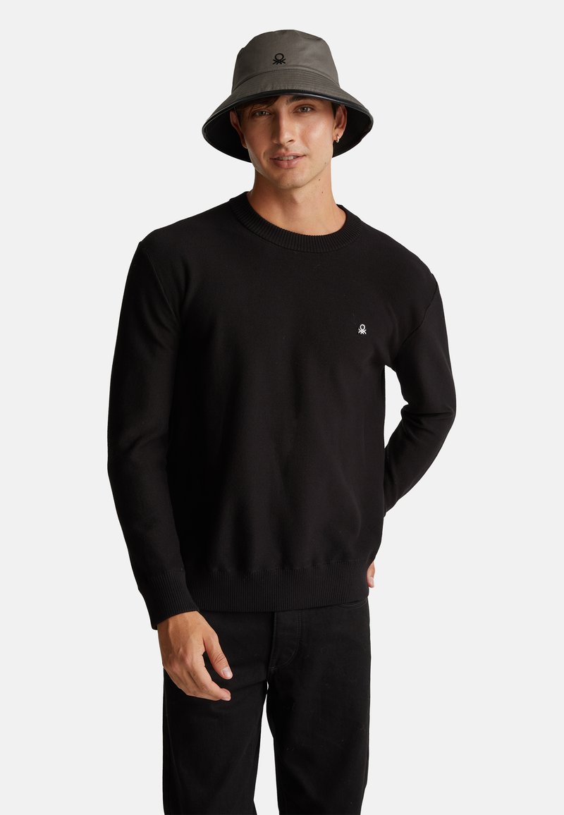 Maglione a maglia nera con scollatura rotonda e orlo a costine, abbinato a pantaloni neri. Presenta un piccolo logo bianco sul petto.